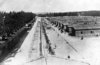 Концентрационен лагер Дахау – общ изглед към бараките, в които са живеели затворниците; оградата от бодлива тел, по която е минавал ток с високо напрежение; бараките на затворниците; април 1945 г. (IPN)