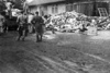 Концентрационен лагер Дахау- затворници освобождават платформата от телата на убитите; на заден план се вижда сградата на крематориума. 1945 г. (IPN)